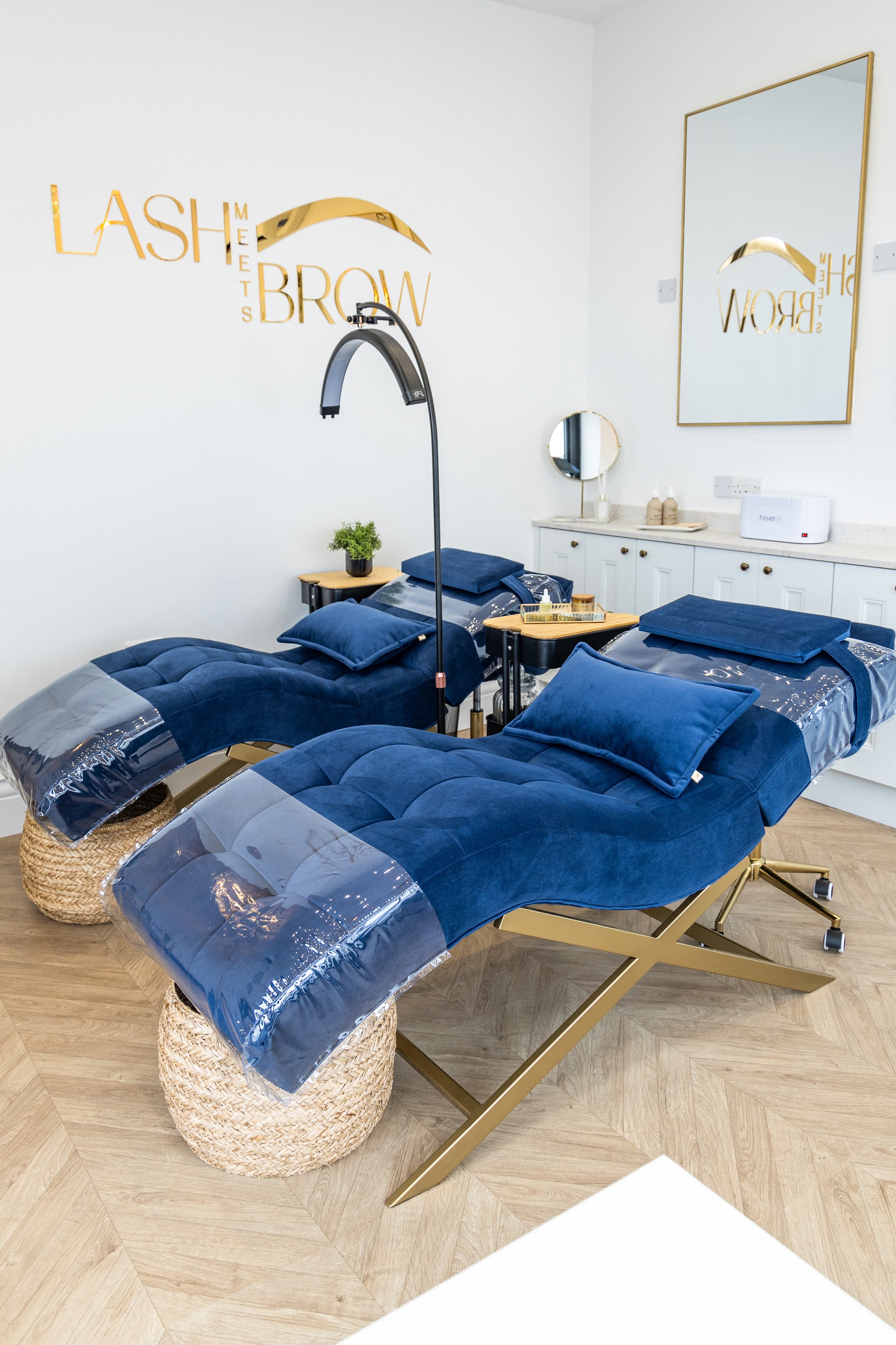 Two navy velvet loungers beside the nail station and gold wall sign