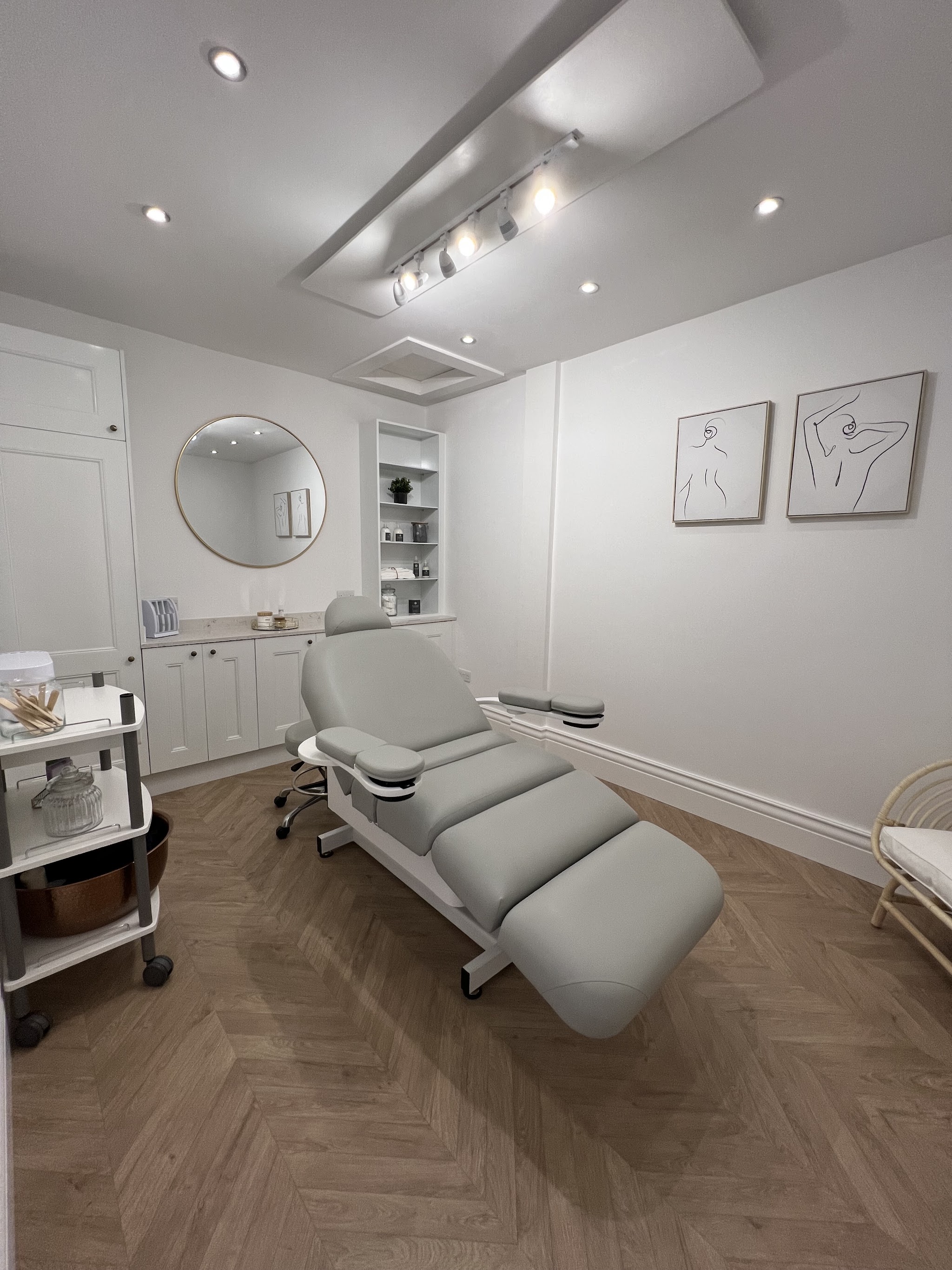 A calm treatment room with a grey couch and herringbone floor